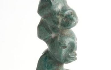 Statuette in green stone representing a seated figure...