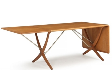 Hans J. Wegner: “AT 304”. Oak dining table mounted on cross legg frame with brass stretchers. Top with fold-down leaves and brass fittings.