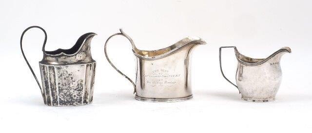 A George IV silver gravy/milk jug, London, 1825, William Eley II, with presentation engraving and crest to sides, 11.6cm high, together with an 18th century Irish silver jug, Dublin, 1797, maker's mark rubbed, 12.5cm high (inc. handle) and a George...