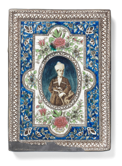 A Qajar underglaze-painted moulded pottery tile depicting a man wearing...