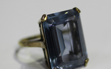 A gold ring, claw set with a large cut cornered rectangular step cut synthetic blue spinel, detailed