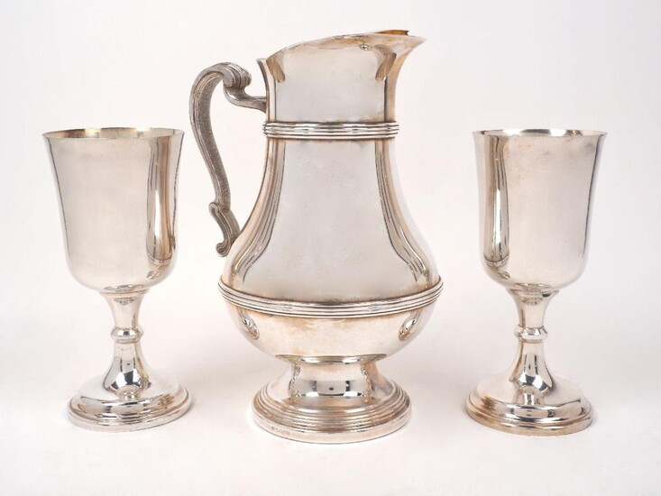 A large silver plated water jug, by Christofle, post 1983, the reeded baluster body with gilded interior to textured scroll handle, the pouring lip with ice trap, 27.5cm high, together with two silver plated Communion cups, one with engraving dated...