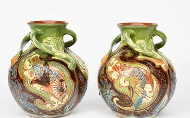A pair of C H Brannam Barnstaple pottery vases by Arthur Babcock, dated 1900, ovoid with flaring neck, applied with three scroll handles to neck, painted in slip and incised with scaly fish swimming amongst waterweed, in green, blue, brown and cream...