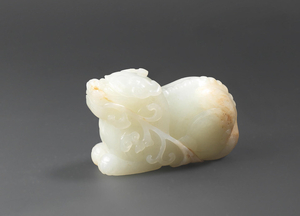 A pale green and russet jade carving of a mythical beast