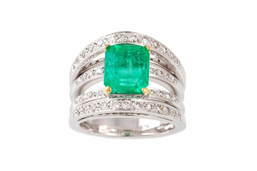 AN EMERALD AND DIAMOND DRESS RING, the trap cut emerald to a...