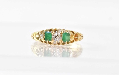 An 18ct gold ring alternately claw set with two emeralds...