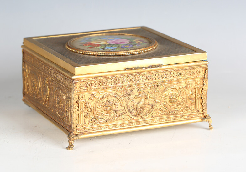 An early 20th century French gilt metal jewellery casket, the top inset with a floral painted porcel