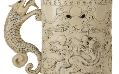 Chope en ivoire, Chine, XXe s., décor de chiens de Fô dans les nuées, anse en forme de chilong, marque Qianlong sous la base, marque Ming