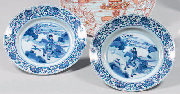 Two china plates. Kangxi (1662-1722), six-character mark, Chenghua, in blue under cover in a double circle. With blue-white decoration, in the center of riders hunting in a landscape in a medallion with circles, the wing of arabesques with lotus...