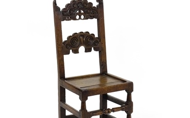 A 17thC oak peg jointed hall chair / back stool with a carve...
