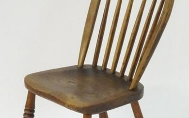 A 19thC elm childs Windsor chair with bowed back and