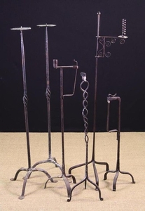 A Collection of Six Wrought Iron Floor Standing Tripod Lights in the 17th/18th century style: A pair of pricket candle-stands with ornamental wrythen 'basket' knops to the stems, 40 ins (102 cm) in height. A peerman with sprung strap jaws above two