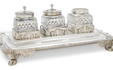 A George III silver inkstand, London, 1811, Thomas & Joseph Guest & Joseph Craddock, the rectangular stand raised on four paw feet with winged bracket shoulders and supporting three square cut glass vessels, one with pierced cover, the second with...