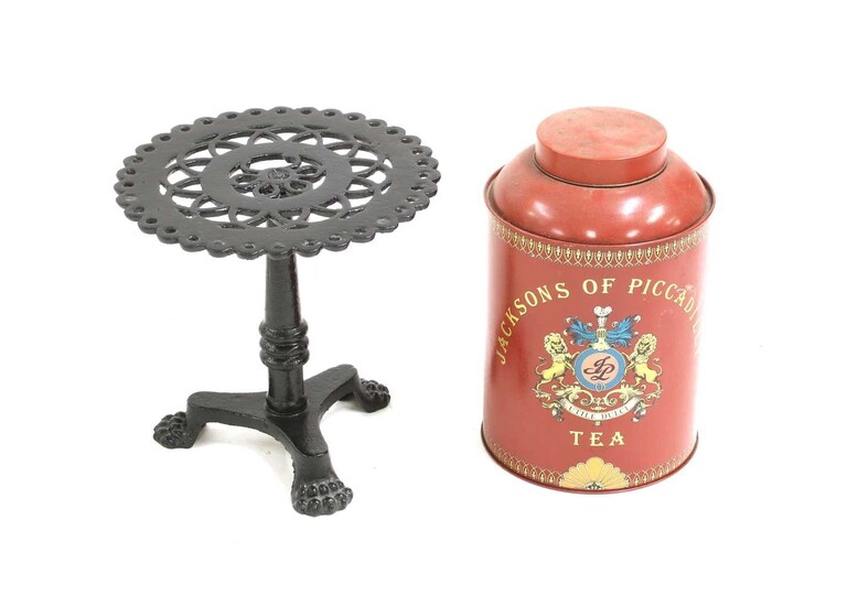 A black painted cast iron trivet in the form of a tripod table