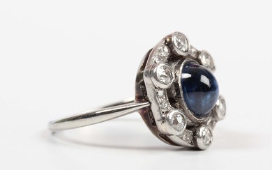 A cabochon sapphire and diamond ring, mounted with the oval cabochon sapphire within an openwork sur
