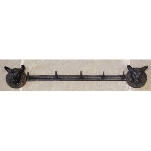 A cast iron wall mounted coat or hat rack, the five hook rai...