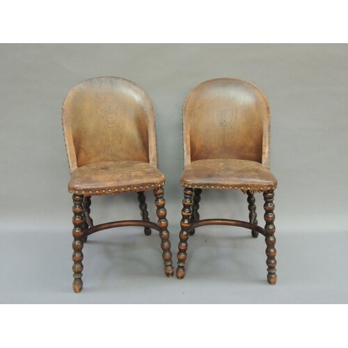 A pair of tan leather and close nailed single chairs, the tu...