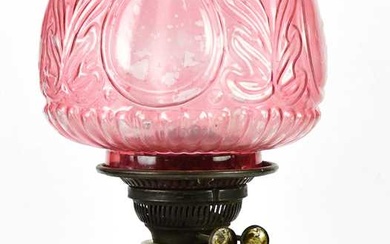 An early 20th century oil lamp with cranberry glass shade...