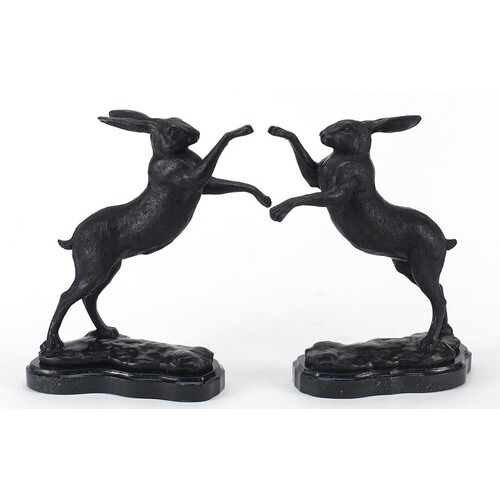 Pair of patinated bronze boxing hares raised on shaped marbl...