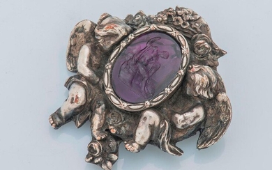 Metal brooch decorated with an amethyst intaglio, depicting Hercules, in a floral decoration supported by two putti. Height: 5.4 cm Width: 5.6 cm Gross weight: 37.7 g