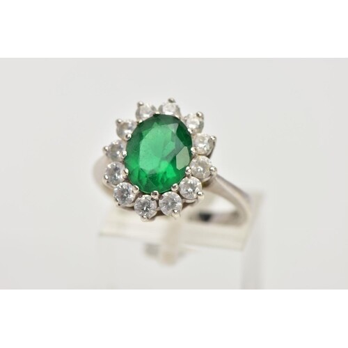 A 9CT WHITE GOLD CLUSTER RING, centring on an oval cut green...