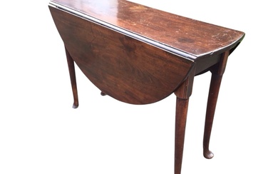 A Georgian mahogany drop-leaf dining table, the circular top with...