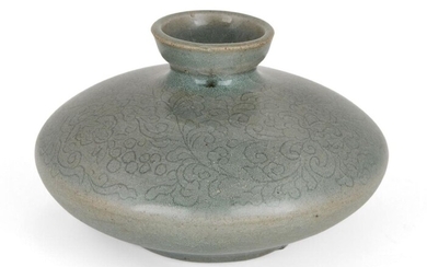 A Korean stoneware celadon oil pot, Goryeo dynasty, of flattened circular form, the exterior decorated with an incised scrolling foliate pattern, covered in an allover sea-green celadon glaze suffused with crackles, 8.5cm wide