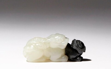 A SMALL CHINESE WHITE AND BLACK JADE CARVING OF LION...