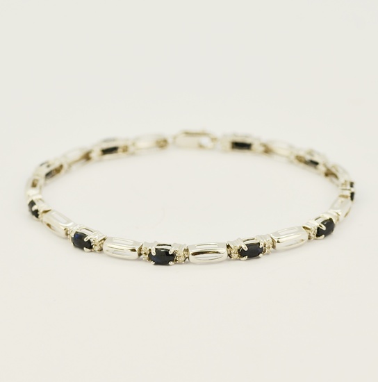 A boxed 10ct white gold bracelet set with oval cut natural sapphires and diamonds, L. 19cm.