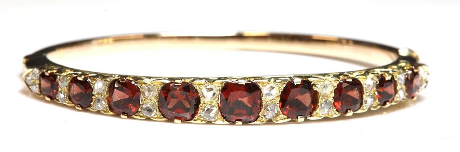 A gold garnet and diamond carved head-style hinged bangle