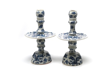 A pair of blue and white porcelain candlestick holders painted with dragons writhing amidst clouds