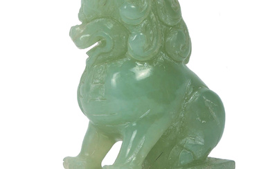 An early 20th century Chinese carved jade Dog of Fo / lion / temple dog. The carving with defensive expression and curled mane, mounted on pedestal base with engraved triangular pattern, 11cm tall.