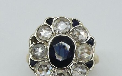 Daisy ring in two golds, the bezel set with an oval sapphire facetted in a setting of T.A. diamonds and small calibrated sapphires. Gross weight 4.9 g. TDD 53 (one sapphire missing)