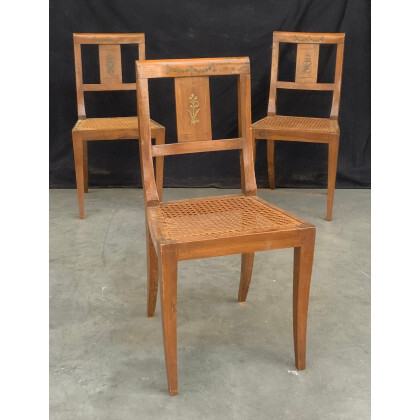 Gruppo di tre sedie in legno con schienale squadrato decorato da applicazioni in metallo a motivi floreali, seduta incannucciata, gambe...