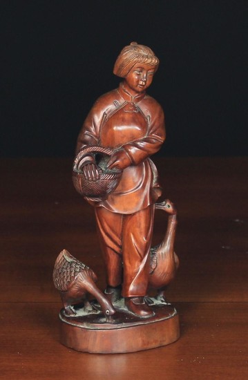 A Chinese Carved Hardwood Figure of a Girl feeding two geese with small inset glass eyes, signed on