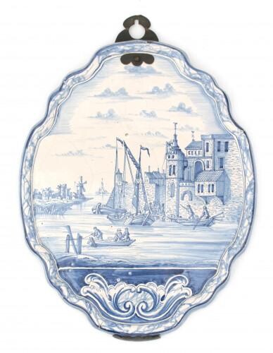 A Delft blue and white earthenware plaque with decoration of a boats in a canal near a fortress, with old mount, 18th century.