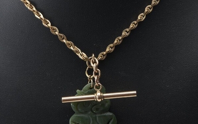 A FANCY LINK FOB CHAIN IN GOLD LINING, ATTACHED TO A 9CT GOLD T-BAR AND PARROT CLASP WITH A NEW ZEALAND NEPHRITE TIKI PENDANT, OVERA...