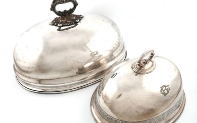 A large old Sheffield plated meat dish cover, unmarked, domed oval form, foliate scroll carrying handle, plus a Victorian electroplated meat dish cover, with a Greek Key border and scroll handle, engraved with initials, lengths 51.5cm and 35.5cm. (2)