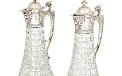 A pair of Garrard & Co. silver mounted cut glass claret jugs, Sheffield, c.1979, the tapering bodies to bifurcated scroll handles with dragon thumbpieces, the hinged domed caps with graduated knop finials, 31cm high (2)