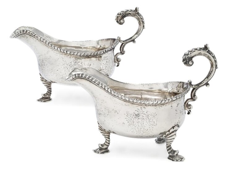 A pair of George II silver gravy boats, London, 1759, William Skeen, each with flying triple scroll handle to gadrooned rim and raised on three moulded legs terminating in shaped pad feet, 16cm high, 22.7cm long (inc. handles), total weight approx...