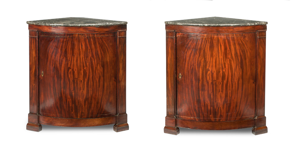 A pair of early 19th century German figured mahogany bowfronted marble top corner cabinets