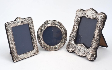 A silver mounted photo frame, repousse decorated with putti and foliate scrolls, London, 1978, CJM, 16 x 21.5cm, together with a circular frame, London, 1987, D.R&S., 14.5cm dia., and a third frame by the same maker, London, 1990, 13.2 x 18cm, all...