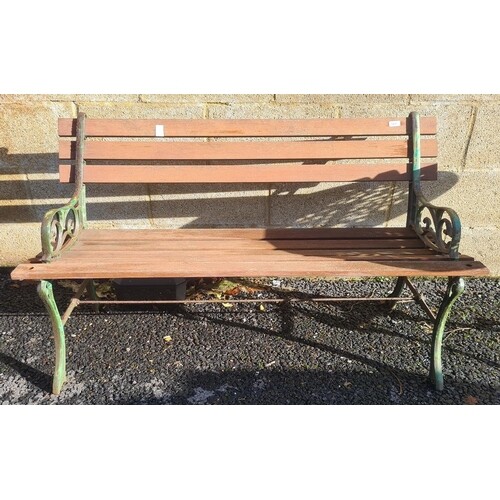 A slatted wood garden bench with metal supports and a white...