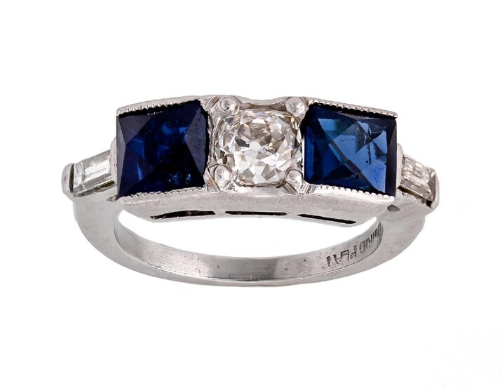 A synthetic sapphire and diamond ring, centring on a cushion-shaped diamond set between a pair of synthetic French-cut sapphires, accented with a pair of baguette diamonds, ring size G
