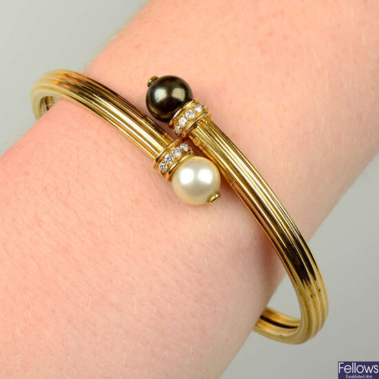 An 18ct gold grooved crossover bangle, with vari-hue cultured pearl and brilliant-cut diamond terminals, by Boodles.