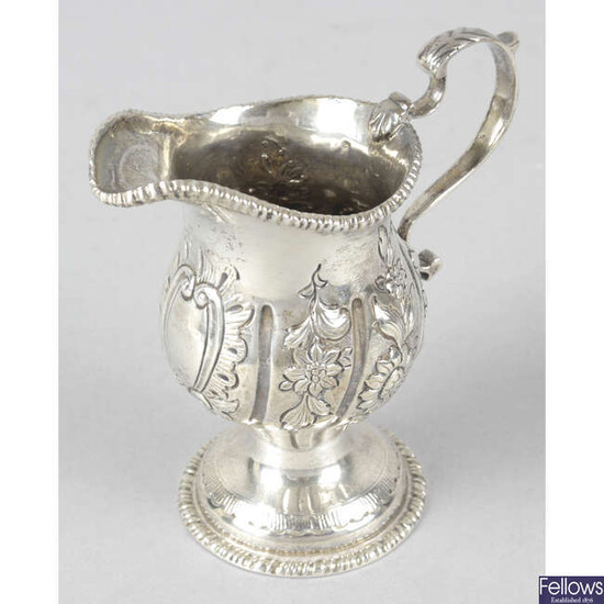An Edwardian silver floral embossed pedestal cream jug.