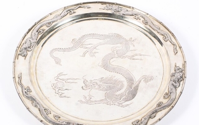 An early 20th century Chinese silver plated circular charger, on three bun feet