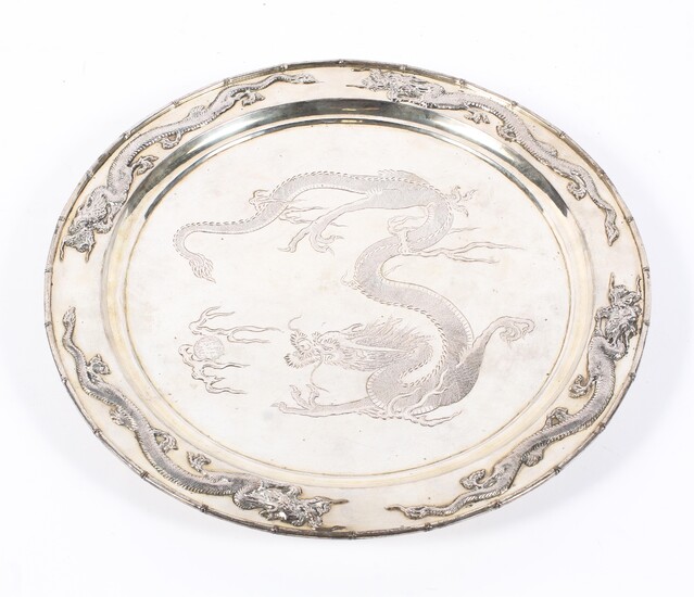 An early 20th century Chinese silver plated circular charger, on three bun feet