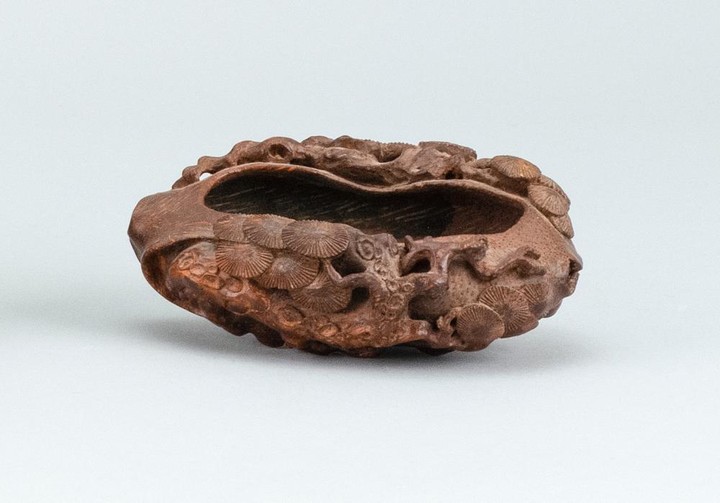 CHINESE CARVED WOOD COUPE In oval form, with carved pine trees, ruyi fungus and roots. Height 1.5". Length 4.25"