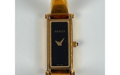 GUCCI. Montre de dame en métal doré. Boîtier rectangulaire, réf. 1500L. Fond noir (30x12mm). Bracelet...